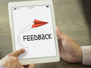 Das Bild zeigt ein weisses Tablet, auf dessen Bildschirm ein gezeichneter roter Papierflieger zu sehen ist, unter dem "FEEBACK" steht